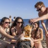 Gruppo di persone accarezza un cane sulla spiaggia.