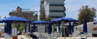 Spiaggia con ombrelloni e due edifici in lontananza.