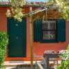 Esterno rosa con tavolo, sedie e pergola fiorita.