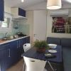 Cucina open space, tavolo blu, sedie bianche, divano, aria condizionata.