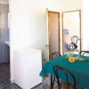 Una sala con tavolo coperto e sedie, piccola cucina visibile.