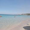 Una spiaggia soleggiata con mare limpido, bagnanti e kayak rosso.