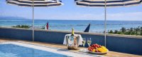 Piscina e tavolo con vino e frutta, ombrelloni blu.