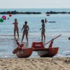 Persone giocano in mare e sulla spiaggia con un pattino.