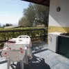 Terrazza con tavolo bianco e vista su alberi e mare.