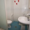Bagno con piastrelle bianche, lavandino e box doccia.