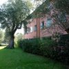 Edificio rosa con prato e alberi intorno.