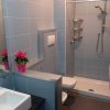 Bagno moderno, piastrelle blu, doccia e fiori rosa.