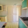 Cucina con armadi verdi, fornelli e pavimento a piastrelle.