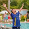 Animatore vicino alla piscina con le braccia alzate.