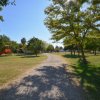 Sentiero ghiaioso in un parco con alberi e area giochi.