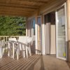 Veranda in legno con tavolo e sedie bianche.