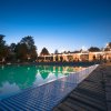Piscina con luci serali e persone in lontananza.