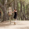 Due persone fanno esercizi su attrezzature in un bosco.
