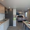 Interno di una casa mobile con cucina, tavolo e letto.