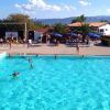 Piscina all'aperto con persone che nuotano e attività sullo sfondo.
