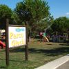 Parco giochi con altalene e scivoli tra alberi verdi.
