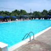 Una grande piscina all'aperto con sedie a sdraio e ombrelloni blu lungo il bordo.