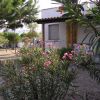 Un giardino con arbusti fioriti e un piccolo edificio bianco con veranda al coperto.