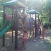Bambini giocano e si arrampicano su una struttura di legno in un parco giochi.