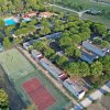 Vista aerea di un campo da tennis e bungalow immersi nel verde.