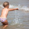 Bambina che gioca nell'acqua, schizzando in mare.