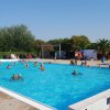 Piscina pubblica affollata, persone che nuotano e si rilassano.