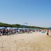 Spiaggia affollata con ombrelloni blu, bagnanti e mare in lontananza.