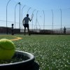 Persone giocano a tennis su un campo sintetico.