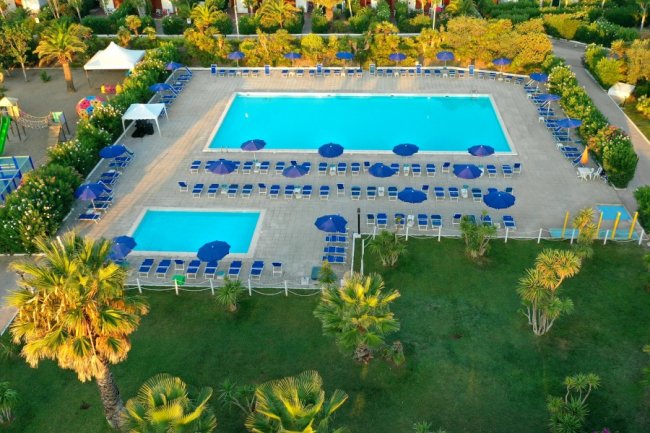 Piscine con lettini e ombrelloni in un giardino.