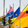Uomini in piedi vicino a vele colorate sulla spiaggia.