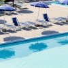 Piscina con sedie a sdraio blu e ombrelloni aperti lungo il bordo.