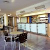 Interno di un bar moderno con tavoli e sedie, un lungo bancone e pavimento lucido.