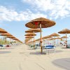Spiaggia con ombrelloni di paglia e lettini disposti in fila su sabbia chiara.