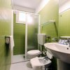 Un bagno con piastrelle verdi, lavabo, bidet e doccia con porta scorrevole.