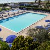 Piscina rettangolare circondata da lettini e ombrelloni blu.