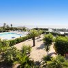 Vista su piscina, area giochi e giardino con palme vicino al mare.