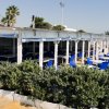 Terrazzino di ristorante con sedie blu e piante in vaso.
