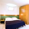 Una camera da letto con letto matrimoniale, copriletto blu e armadio in legno chiaro.
