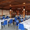 Un ristorante con tavoli apparecchiati e sedie blu, sotto una struttura in legno.