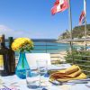 Tavolo apparecchiato con vista mare e fiori gialli.