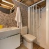 Bagno moderno con doccia, lavandino e specchio rotondo.