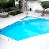 Piscina all'aperto su terrazza con tavolini apparecchiati e piante intorno.