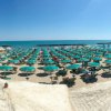 Una vista panoramica su una spiaggia con file ordinate di ombrelloni verdi e il mare sullo sfondo.