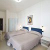 Stanza con tre letti singoli, coperte beige, armadio bianco e scrivania con sedia.