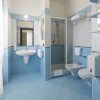 Un bagno con piastrelle blu, lavabo, doccia, WC e bidè.