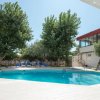 Una piscina circondata da lettini blu e alberi verdi, accanto a un edificio con pareti vetrate.