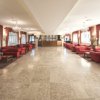 Ampio salone con divani rossi e grandi finestre.