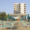 Spiaggia con lettini e ombrelloni verdi, edifici alti sullo sfondo.