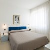 Camera da letto con letto matrimoniale, pareti bianche e testiera blu.